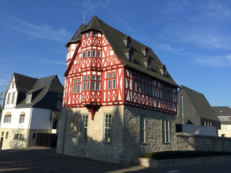 Deutschland - Limburg an der Lahn - Das frisch restaurierte Bischofshaus. 

Das Grundstück des Bischofshaus wird beidseitig von historischen Stadtmauern eingefasst und grenzt unmittelbar an das Diözesanmuseum des Bistums Limburg. Das Diözesane Zentrum umfasst das grundsanierte Haus Staffel (die sog. Alte Vikarie), das ebenfalls sanierte ehemalige Domküsterhaus sowie einen Neubaukomplex. 
Das am 29. Juni 2013 eingeweihte Zentrum war schon während seiner Errichtung Gegenstand nationaler wie internationaler Berichterstattung, da die hiermit verbundenen Kosten zentraler Bestandteil der Kontroverse um den amtierenden Bischof Franz-Peter Tebartz-van Elst waren. Die maßgeblich durch den Bischof zu verantwortenden Mehrkosten führten schließlich im März 2014 zu dessen Rücktritt.