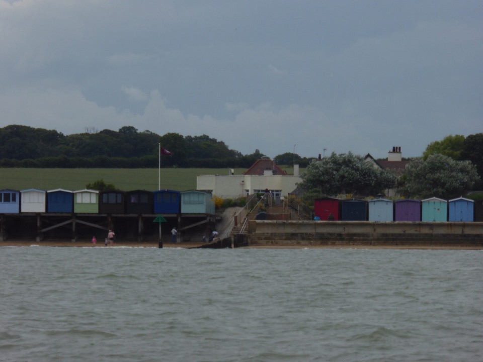 United Kingdom - Ipswich - The Golf Club House visible through a break in the beachhuts.