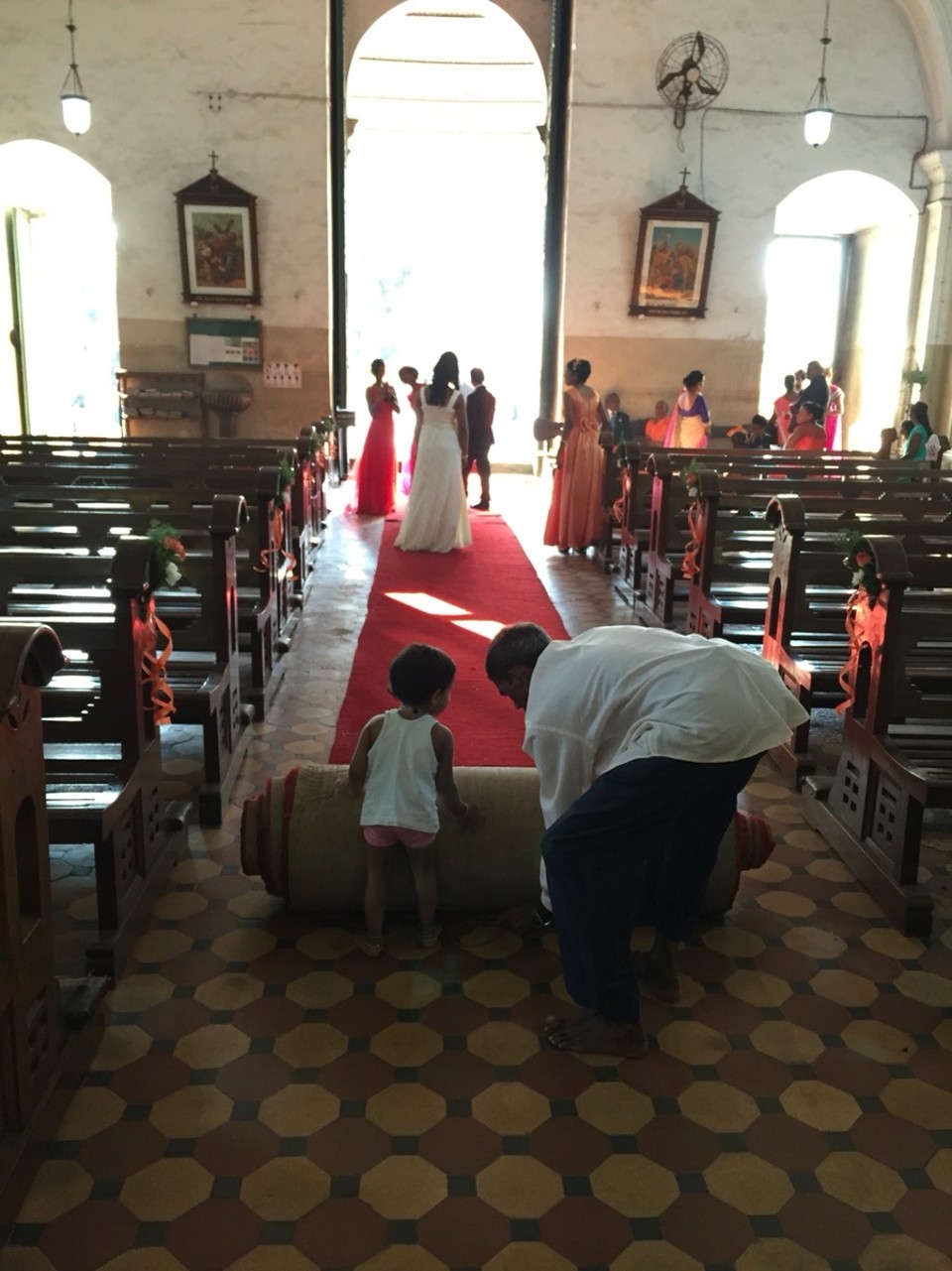 Indien - Sasashti - Hochzeit. Das Brautpaar schreitet aus der Kirche (und steht noch auf dem roten Läufer, dahinter wird aufgeräumt/aufgerollt.
Der/eine oder andere war auch schon mal in dieser Kirche!