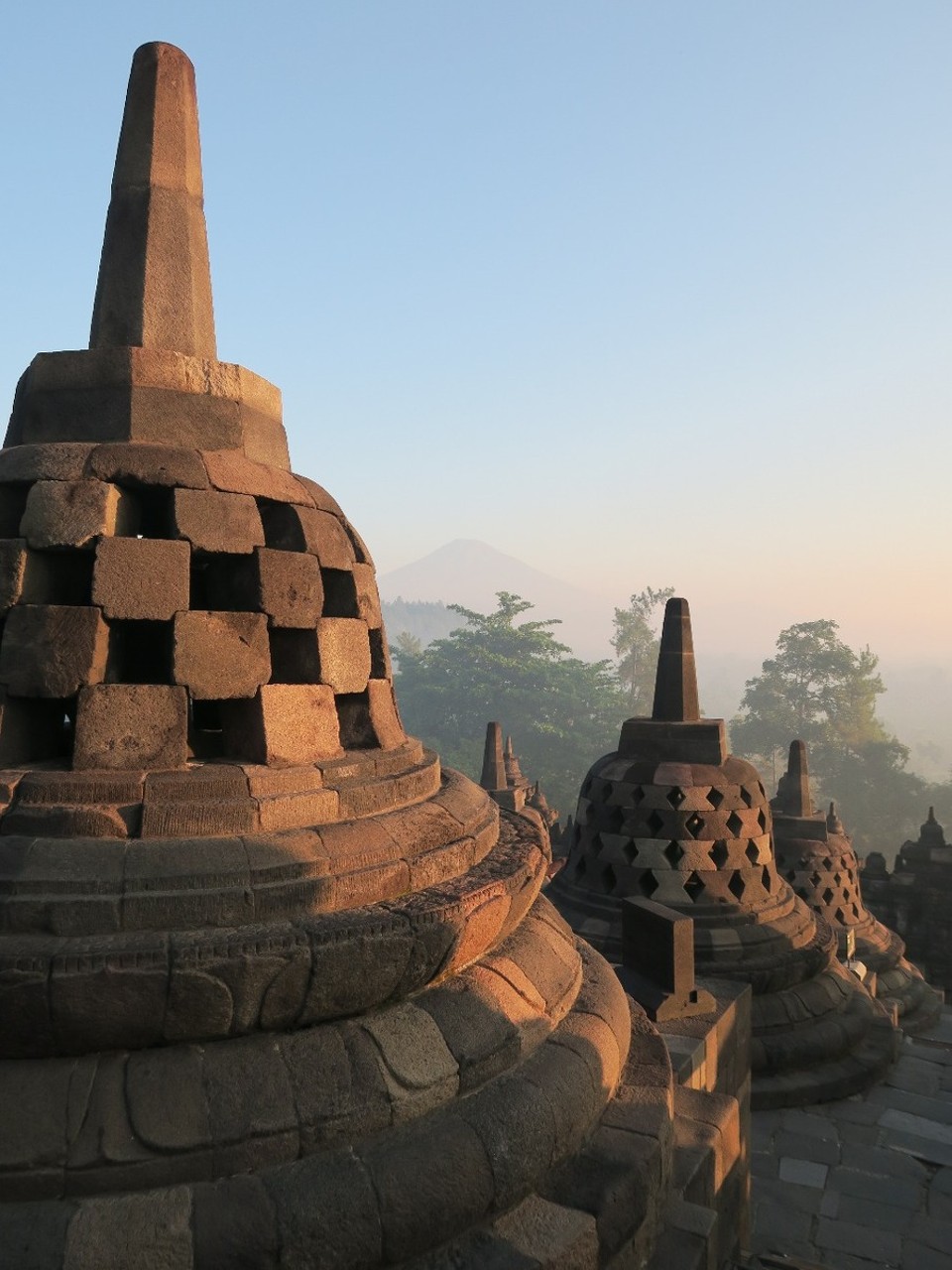 Indonesia - unbekannt - Stupas ajourees en pierre volcanique avec au fond le volcan Merapi