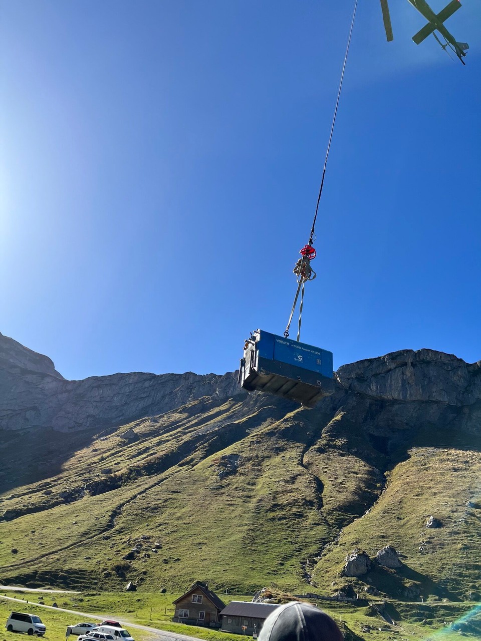 Schweiz - Urnerboden - Er hat offenbar Zement nach oben geflogen und bringt nun diverse Geräte wieder nach unten. Oben arbeiten sie anscheinend an einer Wasserleitung.