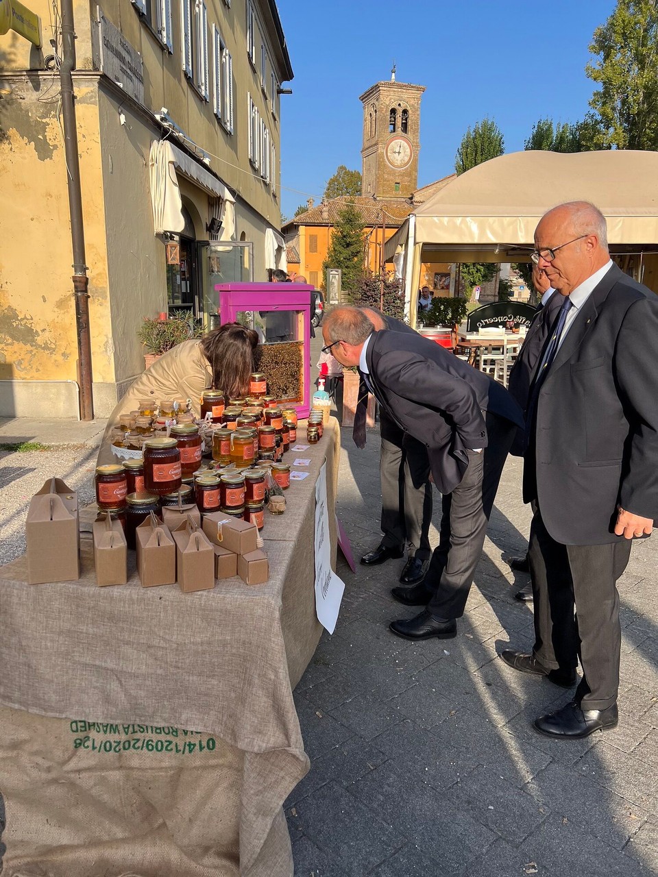 Italien - Busseto - Vis à vis hat es einen kleinen Stand mit verschiedenen Arten von Honig.Diese Männer lassen sich gerade die Bienenkönigin zeigen. Weder Honig noch Bienenkönigin haben jedoch etwas mit ihrem „Vorort-sein“ zu tun😉😌