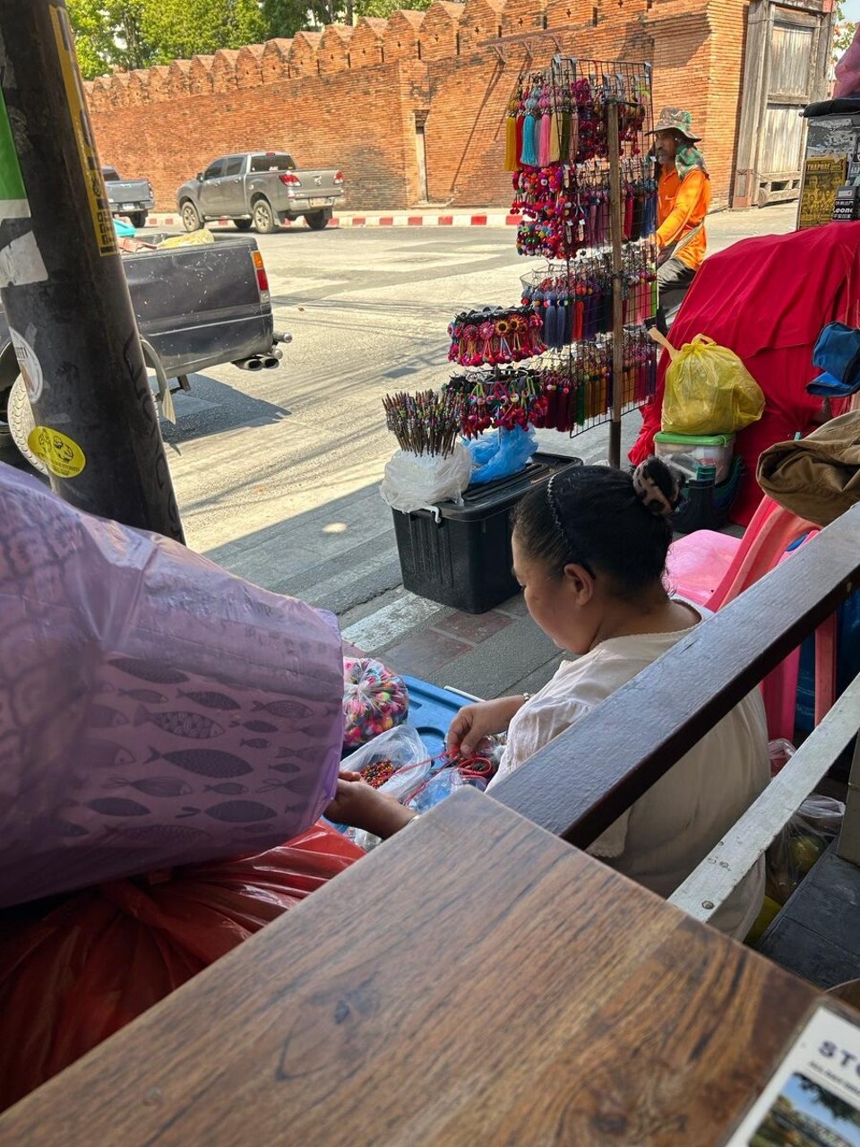 Thailand - Chiang Mai - Während unseres Frühstücks wurde schon fleißig für den Markt ab 17 Uhr vorbereitet. Diese Dame baut gerade ihren Stand auf. Nebenbei hat sie gemütlich gefrühstückt. Bereitet den Stand weiter vor und verkauft zwischendurch Selbstgemachtes.
