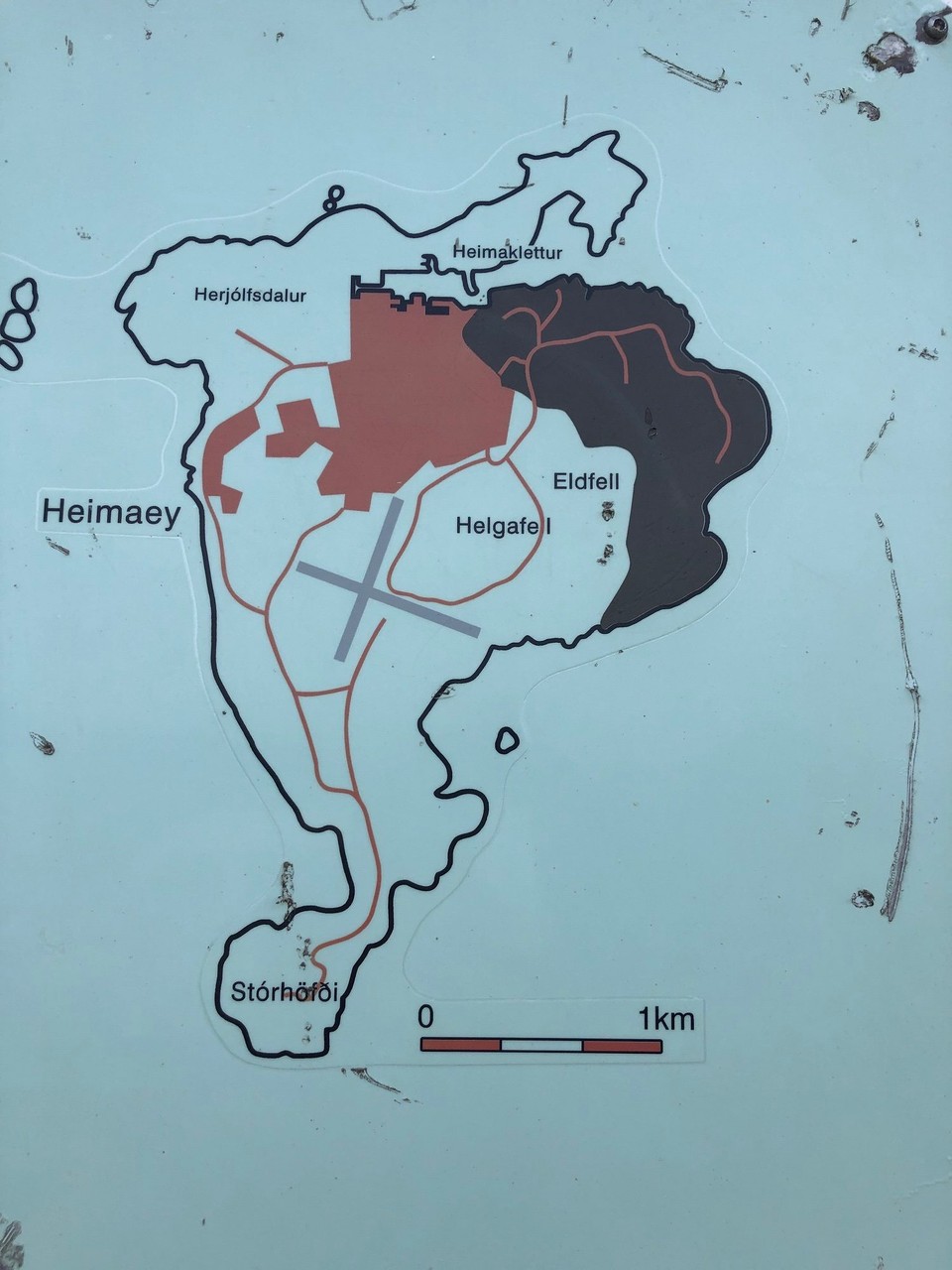 Island - Vestmannaeyjar - Hier sieht man schön, welche Auswirkungen der Vulkanausbruch hatte: schwarz ist neu gebildete Landfläche und rot ist von Lava überschwemmte Landfläche… die Anstrengungen dem Hafen zu retten haben sich aber echt gelohnt… ganze Arbeit wurde da geleistet…