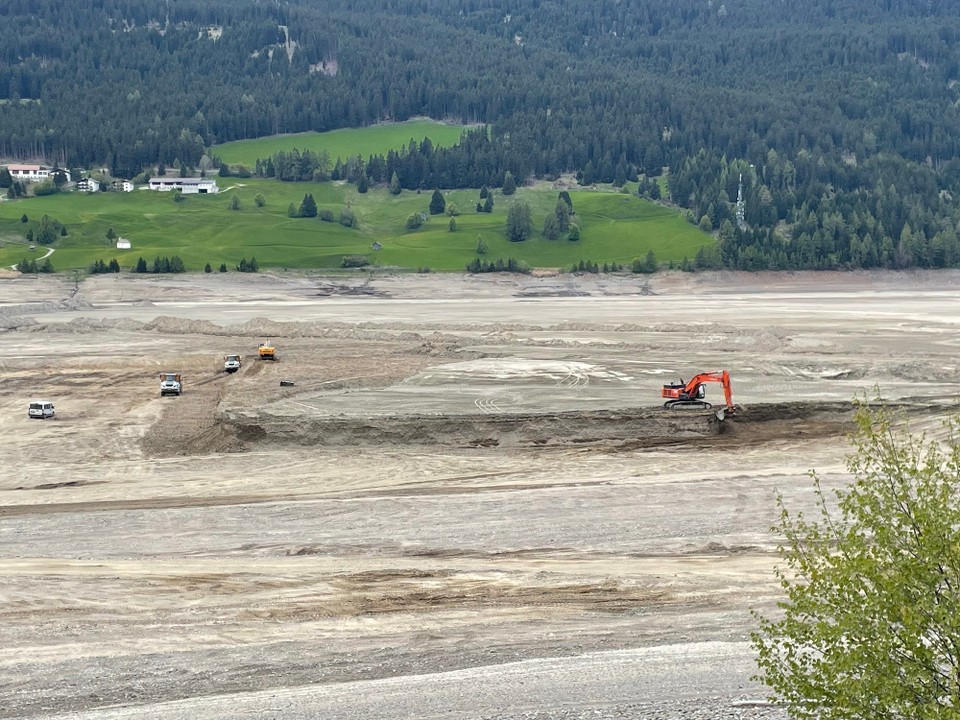 Italien - Graun im Vinschgau - Es wird eine Umgehungsstraße gebaut. Dadurch wurde der See abgelassen. Wie viele Lastwagen da herumfahren. Und eine fast endlose Aufgabe, bis da eine 50 Meter breite und ??? Meter hohe Straße aufgeschüttet ist.  