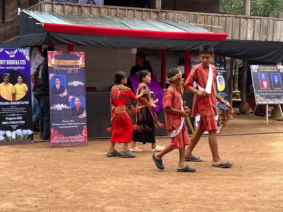 Indonesien - North Toraja Regency - Die Jungend ist festlich rot gekleidet, alle Erwachsen tragen schwarze/dunkle Kleidung, oder weiß je nach Stellung in der Gesellschaft.